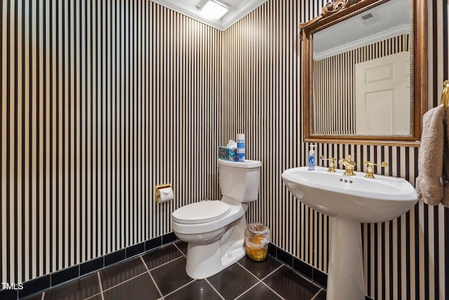 bathroom with toilet, tile patterned floors, wallpapered walls, crown molding, and baseboards