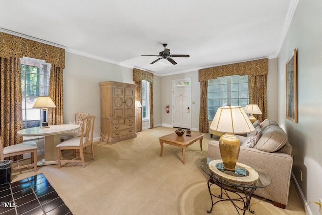 carpeted living area with crown molding, healthy amount of natural light, ceiling fan, and baseboards