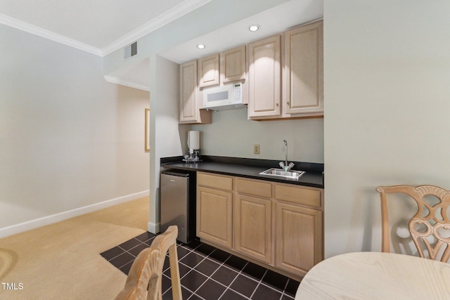 kitchen with white microwave, a sink, light brown cabinets, dark countertops, and crown molding