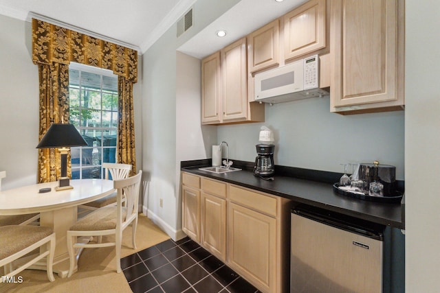 kitchen with a sink, white microwave, light brown cabinetry, fridge, and crown molding