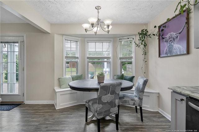 dining area with a healthy amount of sunlight, dark wood-style floors, a textured ceiling, and a notable chandelier