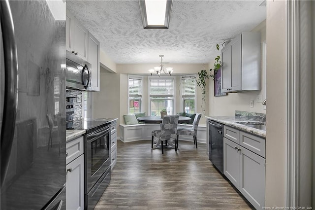 kitchen featuring dark wood-style flooring, appliances with stainless steel finishes, hanging light fixtures, a textured ceiling, and a chandelier