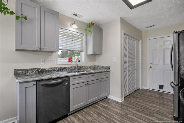 kitchen with appliances with stainless steel finishes, gray cabinetry, baseboards, a sink, and dark wood-style floors