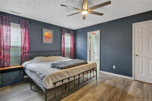 bedroom with a textured ceiling, visible vents, and wood finished floors