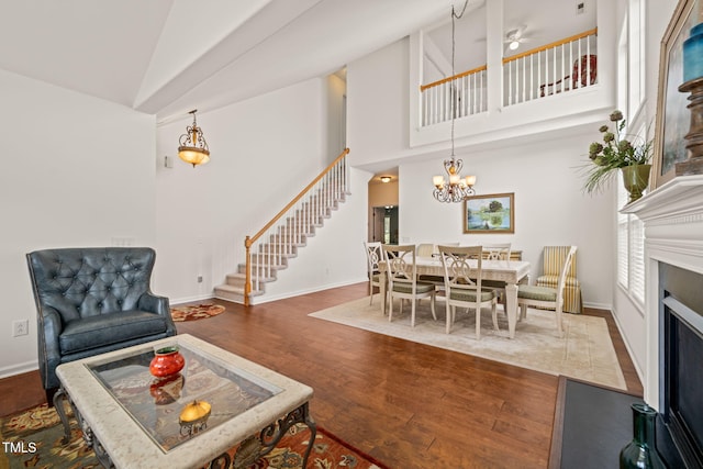 living area with baseboards, stairs, high vaulted ceiling, and wood finished floors