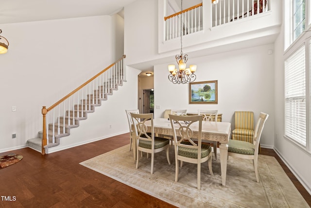 dining room with stairs, a notable chandelier, a high ceiling, and wood finished floors