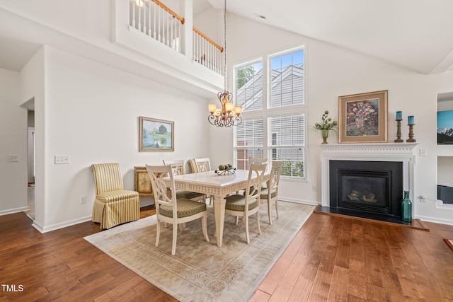 dining space featuring an inviting chandelier, baseboards, hardwood / wood-style floors, and high vaulted ceiling
