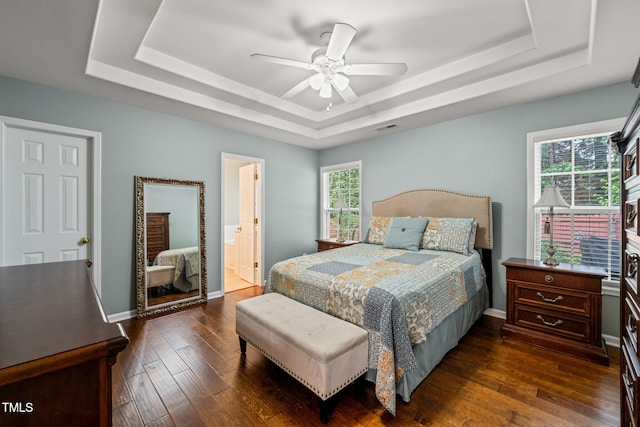 bedroom featuring a tray ceiling, multiple windows, dark wood finished floors, and ceiling fan