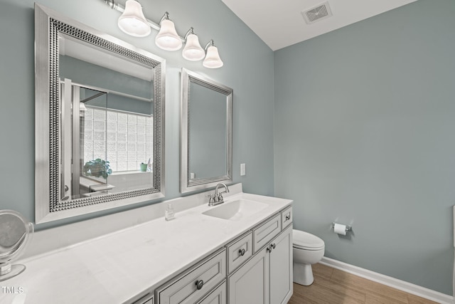 full bath with toilet, baseboards, visible vents, vanity, and wood finished floors