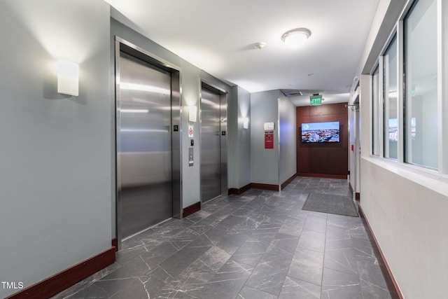 hall with baseboards, marble finish floor, and elevator