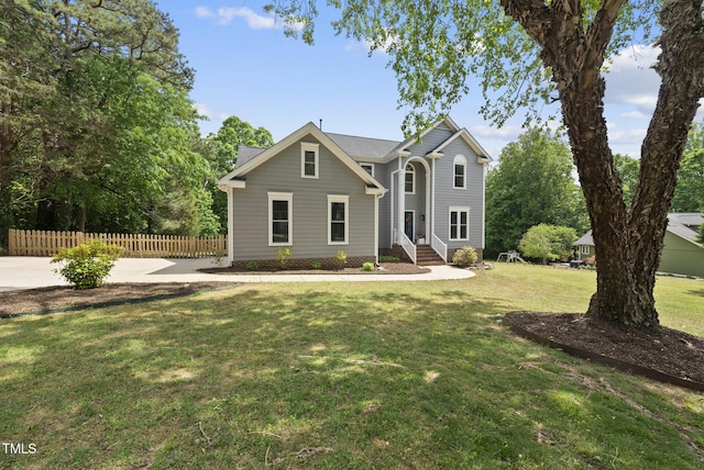 traditional-style home featuring fence, a front yard, and entry steps