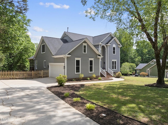 traditional-style house with a garage, fence, a front yard, a shingled roof, and driveway