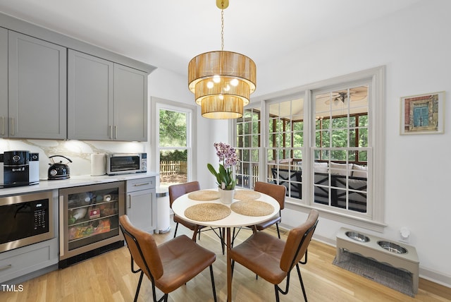 dining space with light wood-style floors, a toaster, and beverage cooler
