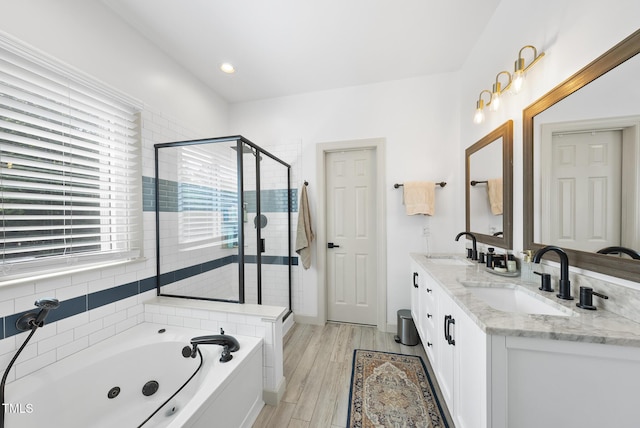 bathroom with a tub with jets, a sink, double vanity, and a shower stall