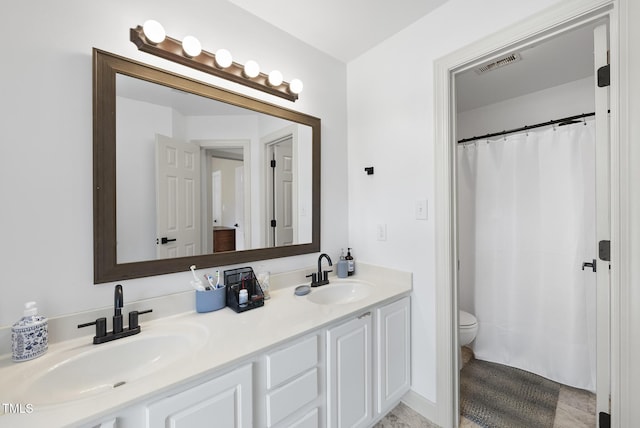 full bath featuring visible vents, a sink, double vanity, and toilet