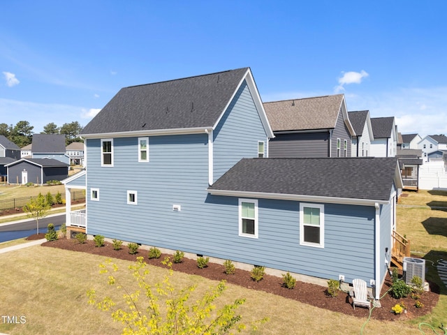 rear view of house with a residential view, a yard, a shingled roof, and cooling unit