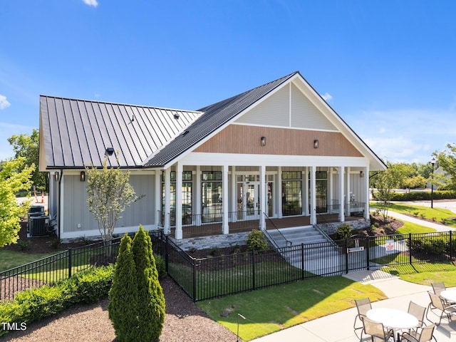 back of house featuring a porch, a fenced front yard, a standing seam roof, and metal roof