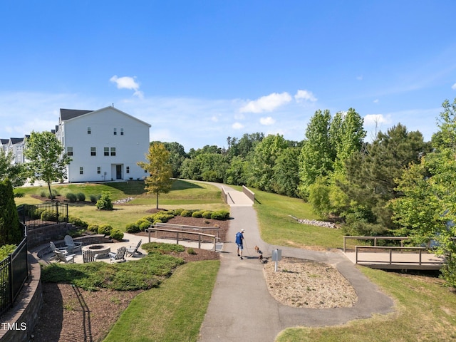 view of home's community with a lawn, fence, and a fire pit