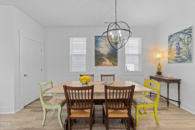 dining room featuring baseboards, light wood-style flooring, a chandelier, and visible vents
