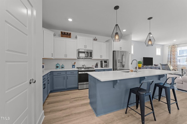 kitchen featuring a sink, light countertops, stainless steel appliances, open floor plan, and decorative backsplash