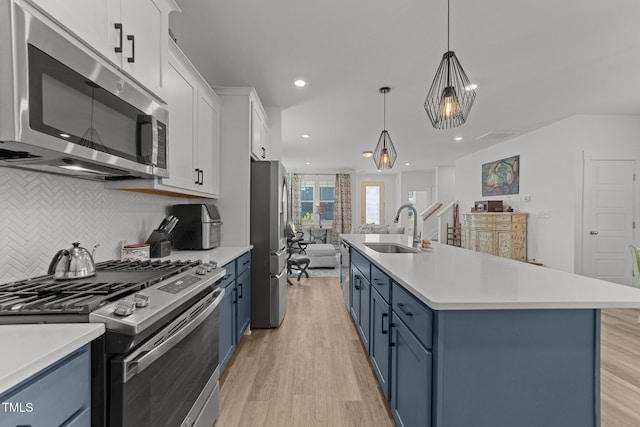 kitchen with stainless steel appliances, light wood-style floors, a sink, and blue cabinets