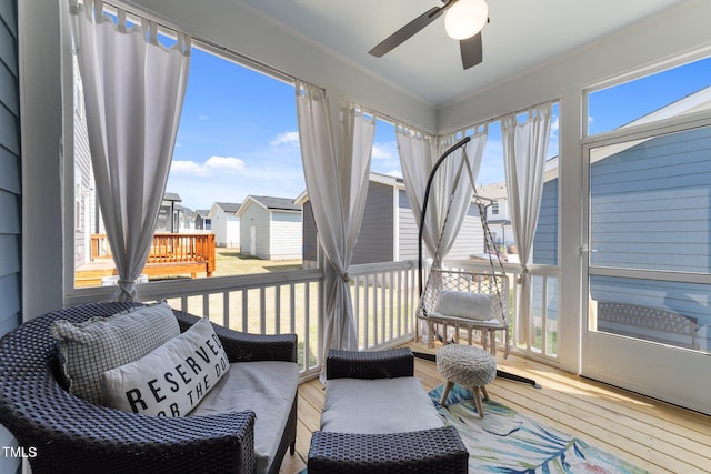 sunroom with a residential view, a ceiling fan, hardwood / wood-style floors, and a wooden deck