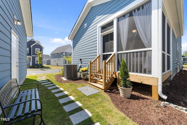 exterior space featuring a sunroom, entry steps, a residential view, and cooling unit