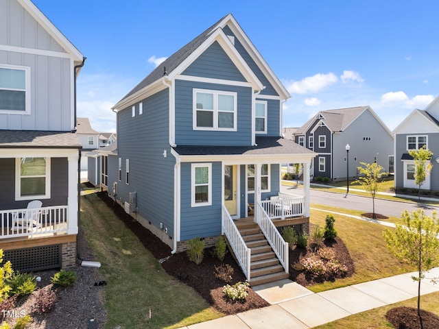 view of front of home with a porch, crawl space, board and batten siding, stairway, and a front lawn