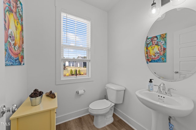 bathroom featuring toilet, baseboards, a sink, and wood finished floors
