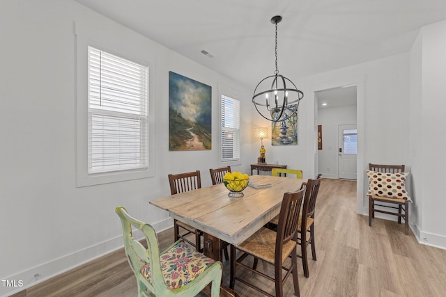 dining room with an inviting chandelier, baseboards, light wood-style flooring, and visible vents