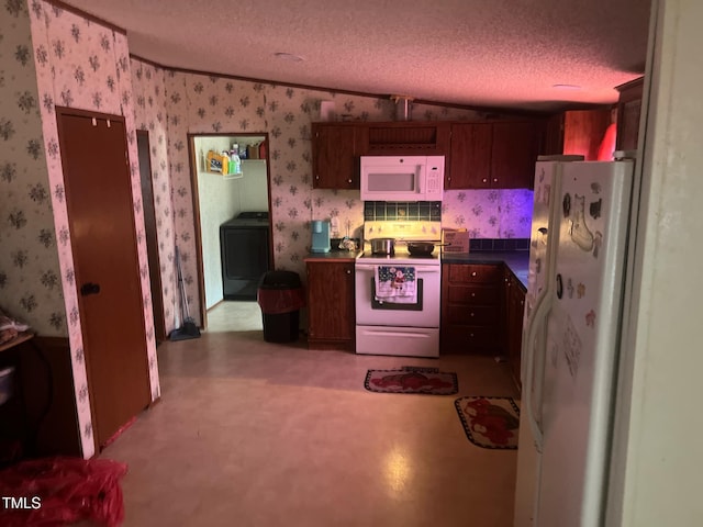 kitchen with washer / dryer, dark countertops, white appliances, wallpapered walls, and a textured ceiling