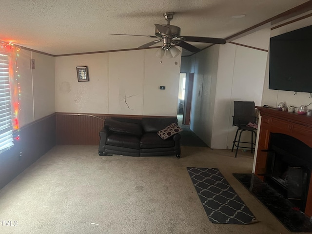 living area with a ceiling fan, a textured ceiling, wainscoting, and carpet