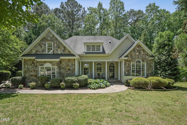 view of front of house with stone siding, a front lawn, and a porch