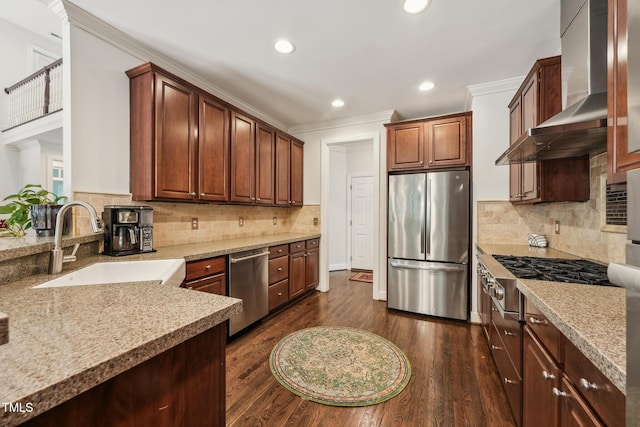 kitchen featuring appliances with stainless steel finishes, a sink, crown molding, wall chimney exhaust hood, and recessed lighting