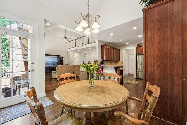 dining space with dark wood-style flooring, ceiling fan, recessed lighting, high vaulted ceiling, and a chandelier