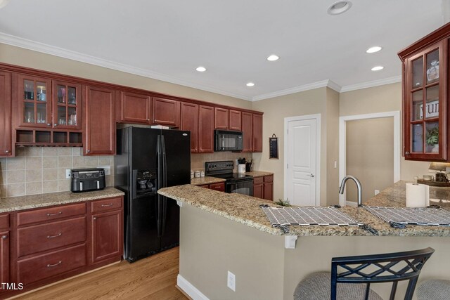 95 Live Oak Dr, Louisburg, NC 27549 - kitchen with black appliances, a peninsula, a kitchen breakfast bar, light wood-style flooring, and tasteful backsplash