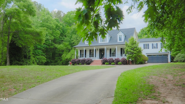 new england style home with a garage, covered porch, driveway, and a front lawn