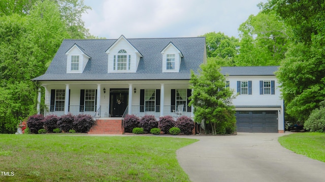 new england style home with concrete driveway, a garage, a porch, and a front lawn