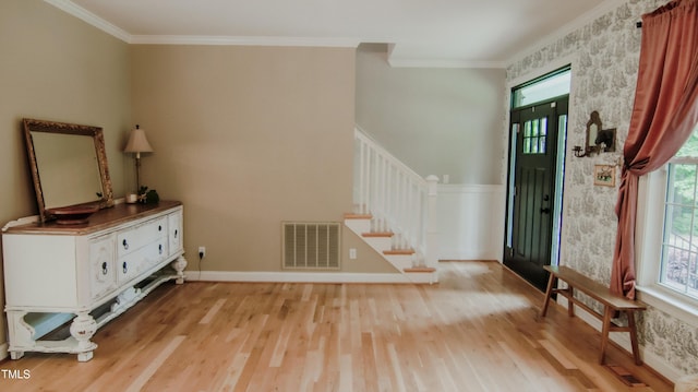 foyer entrance with a healthy amount of sunlight, light wood-type flooring, stairs, and visible vents