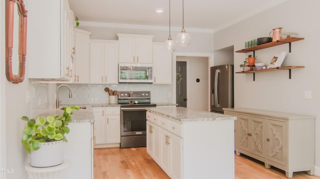 kitchen with a sink, appliances with stainless steel finishes, decorative backsplash, and ornamental molding