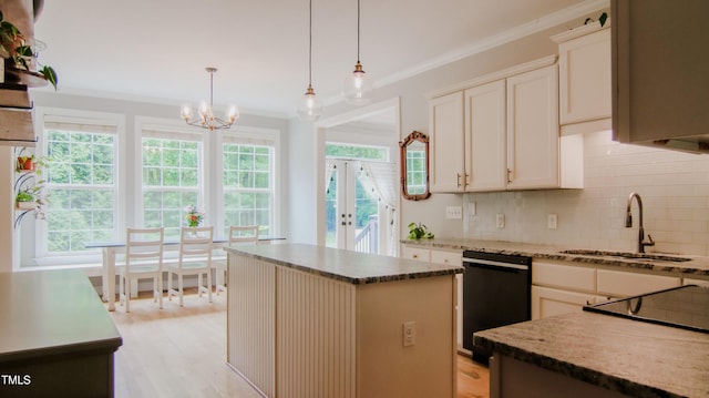 kitchen with decorative backsplash, crown molding, dishwasher, a sink, and a chandelier