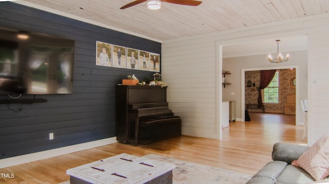 living area featuring wooden walls, wooden ceiling, ceiling fan with notable chandelier, and wood finished floors