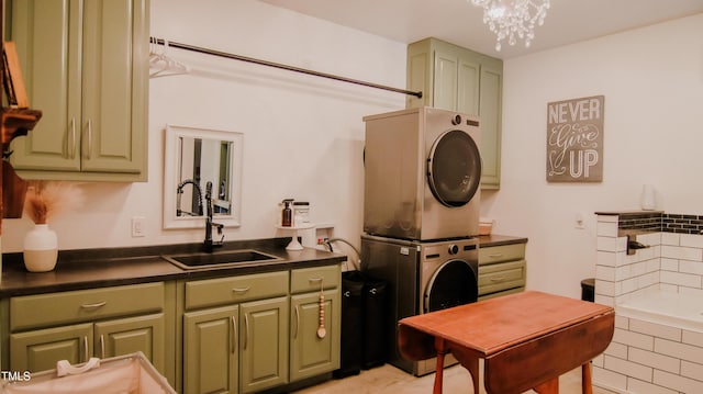 laundry room with stacked washer and clothes dryer, a sink, cabinet space, and a chandelier