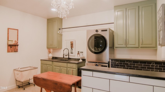 laundry area with stacked washer / dryer, recessed lighting, an inviting chandelier, and a sink