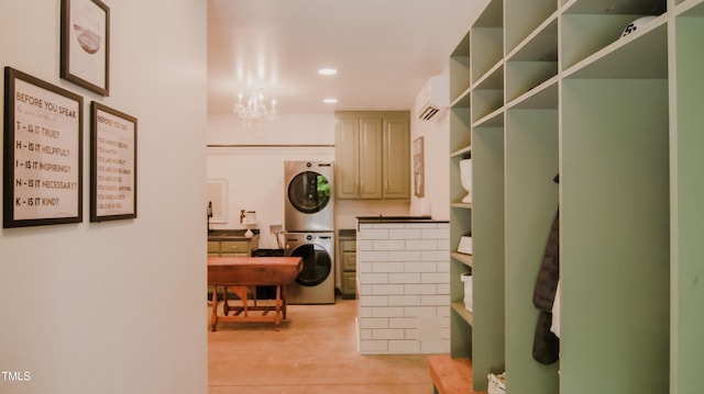 washroom with an inviting chandelier, laundry area, a wall mounted air conditioner, light wood-style flooring, and stacked washer / drying machine
