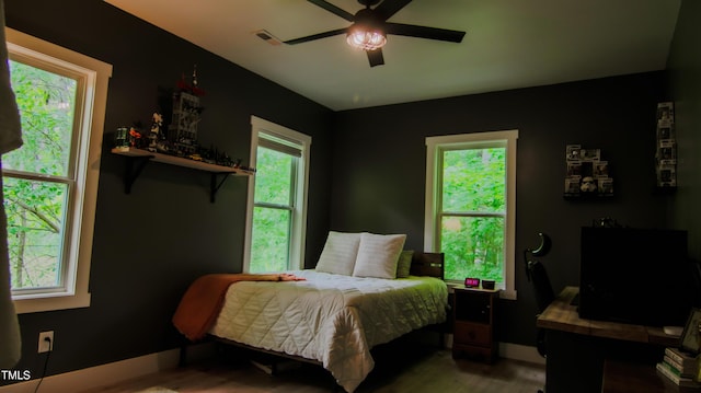 bedroom with a ceiling fan, baseboards, visible vents, and wood finished floors