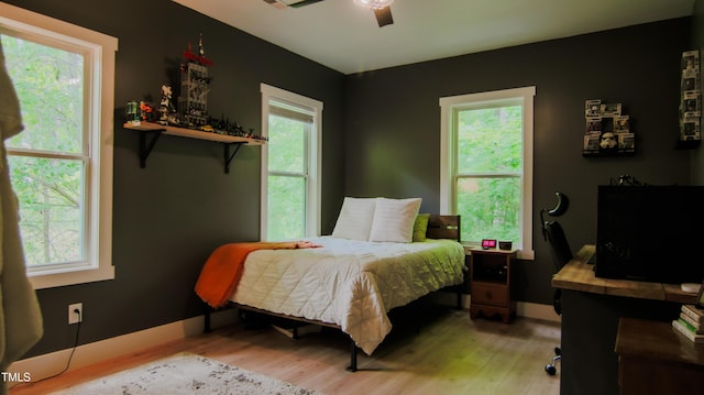 bedroom with multiple windows and light wood-style flooring