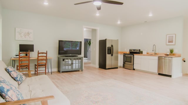 living room featuring a ceiling fan, baseboards, recessed lighting, and light wood-style floors
