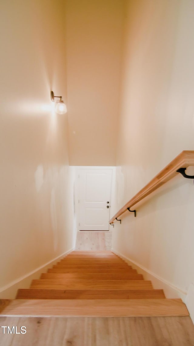 staircase featuring baseboards and wood finished floors