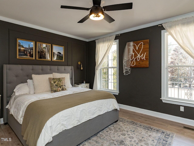 bedroom with crown molding, multiple windows, wood finished floors, and visible vents